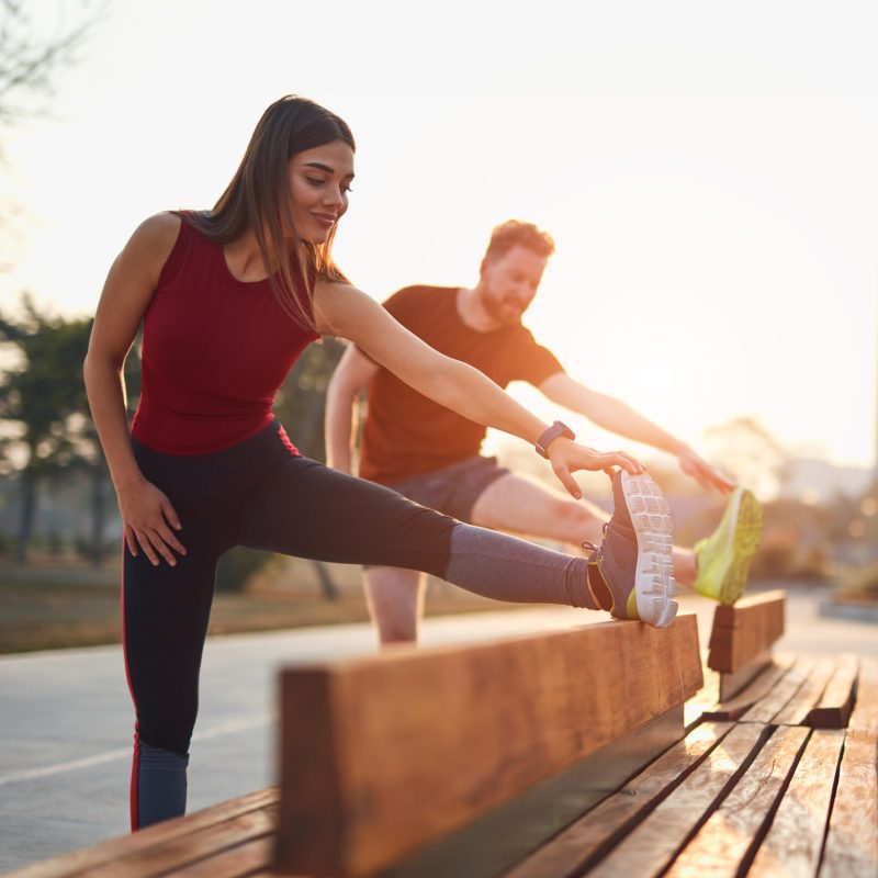 Two young sporty man and woman exercising in urban park.